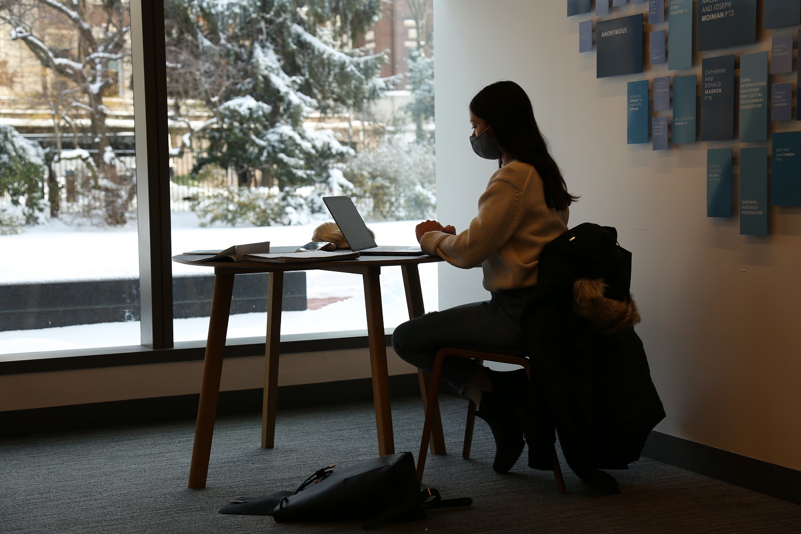 Student sitting at a table with mask on in Milstein studying.