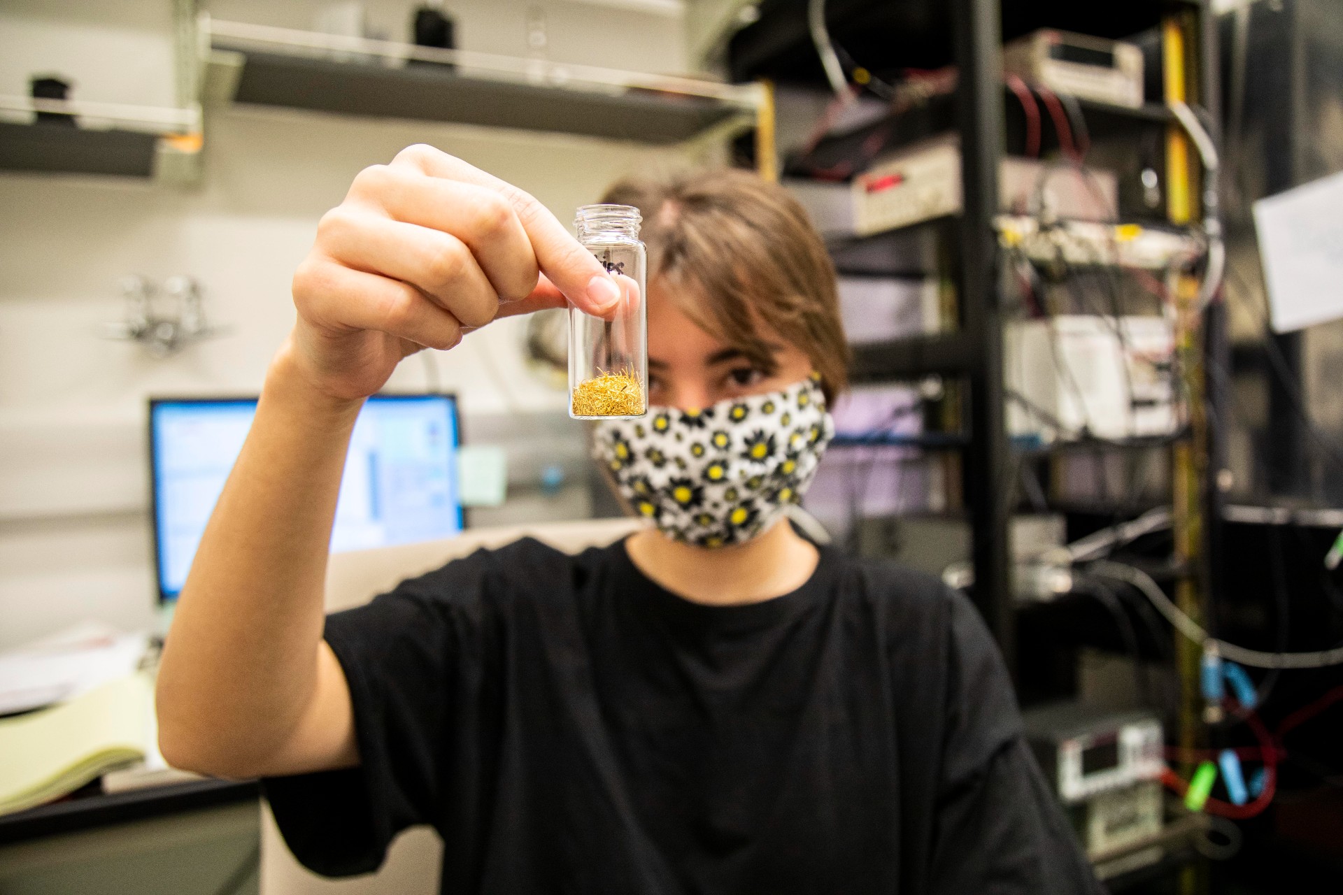 Iris Liu ’22 in the lab holding up the gold particles she uses to study light emissions