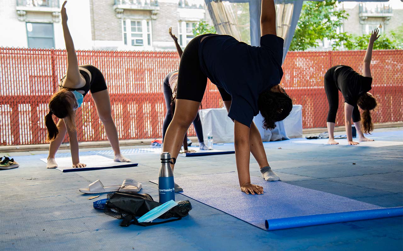 Four students in a yoga class perform the same stretch with one arm toward the sky