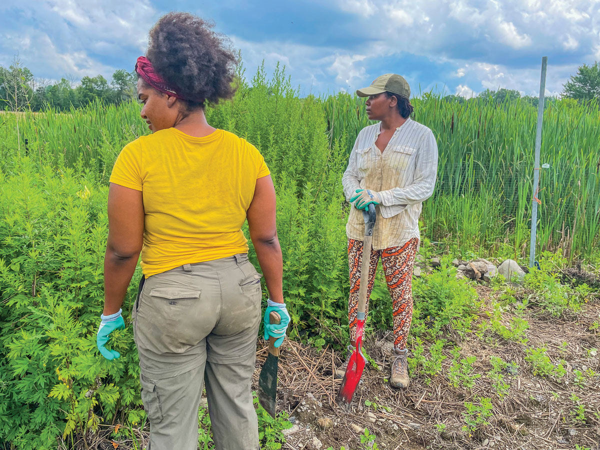 Two people stand in a field taking a break from digging.