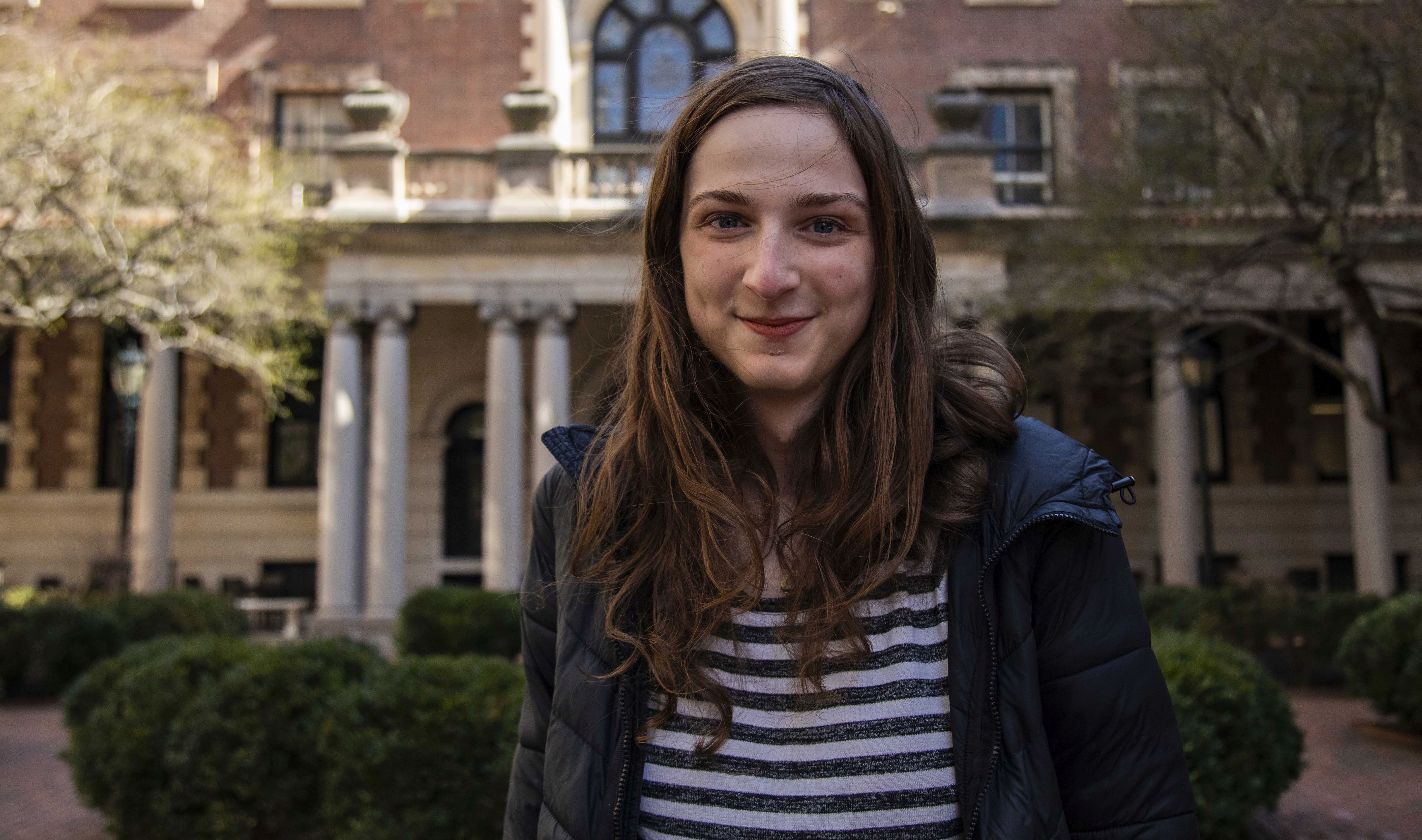 Katherine posing in front of Milbank wearing a striped shirt and sweater.