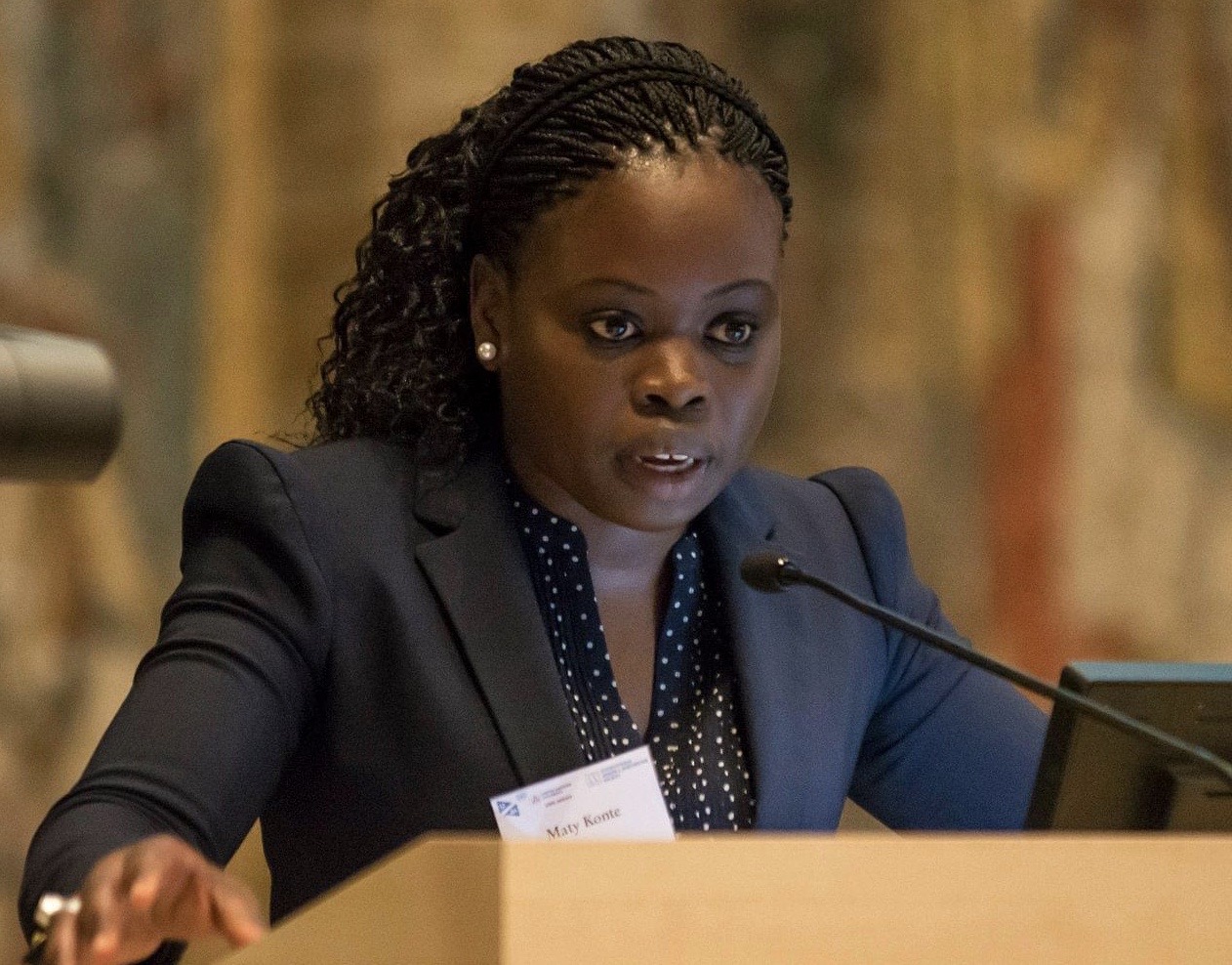 Research Scholar of Economics Maty Konte stands at a podium in a black suit jacket