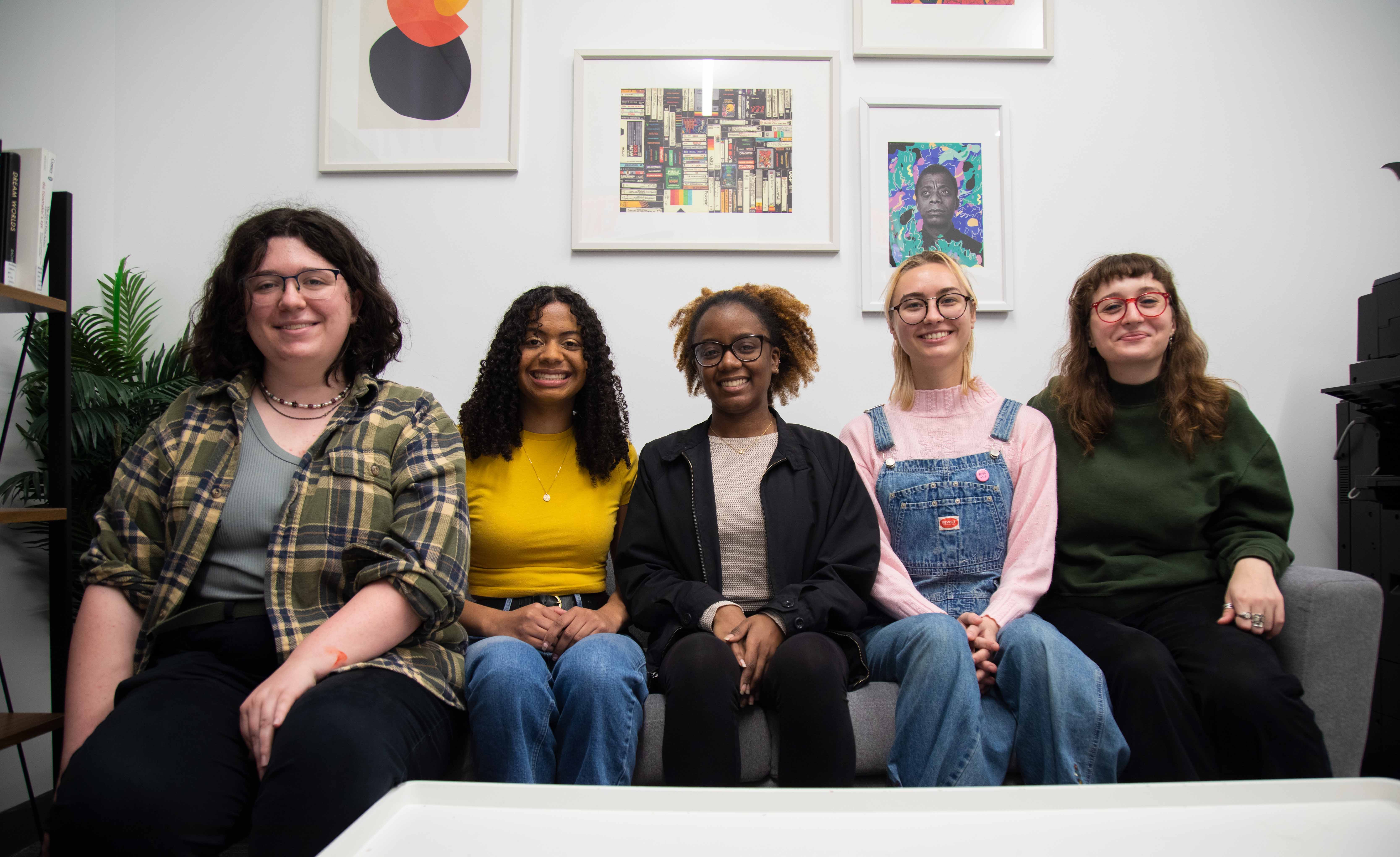 The five senior physics and astronomy majors sit side by side on a couch.