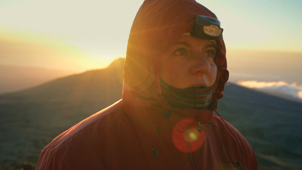 Filmstill from KiliBig of woman on mountain top in a orange coat