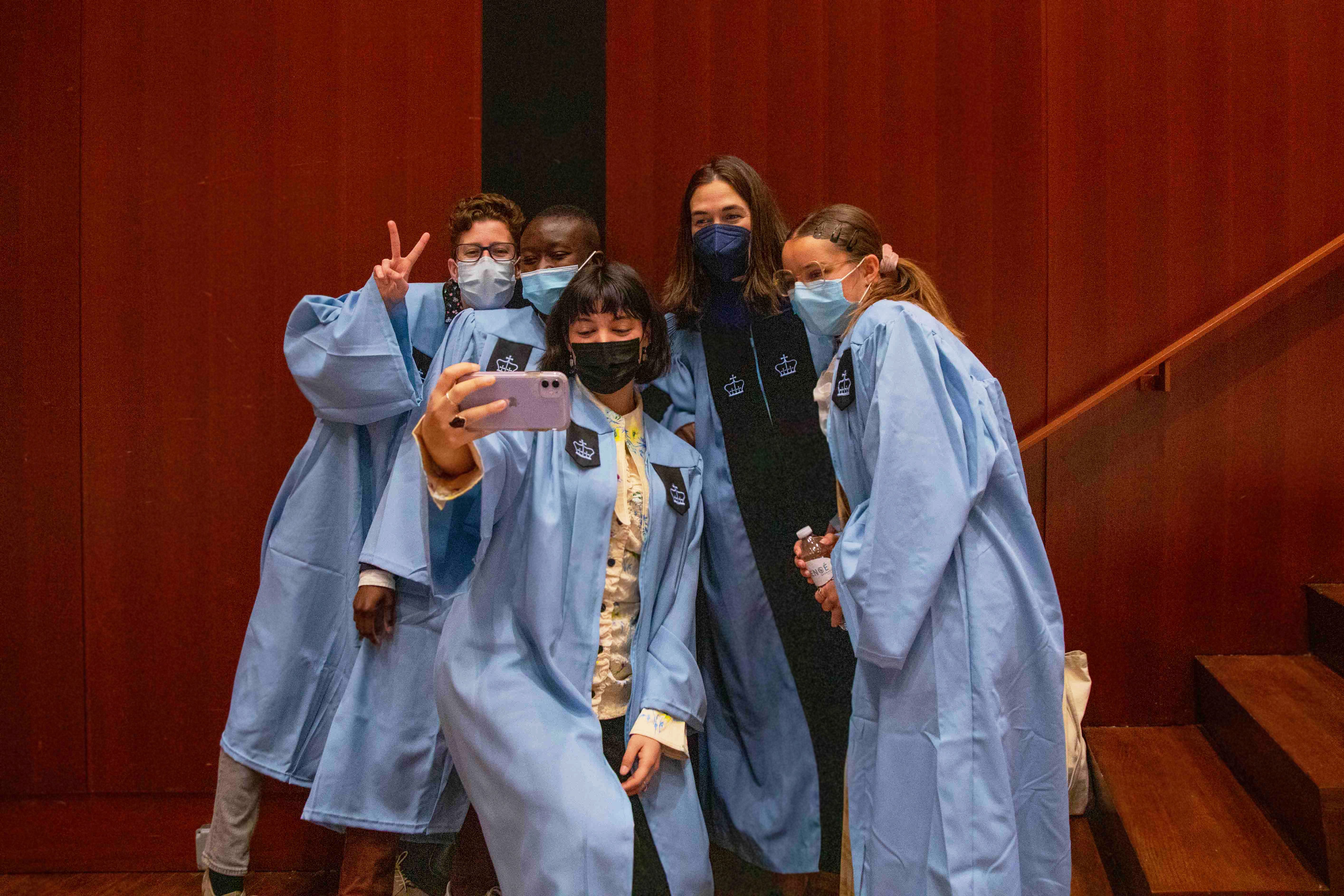 A group of students in caps and gowns pose around President Beilock for a selfie.