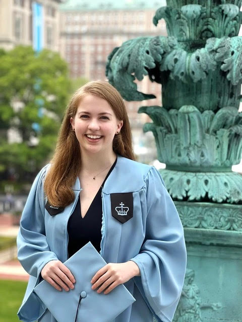 Abby in her cap and gown in front of some kind of green statue on Columbia's campus