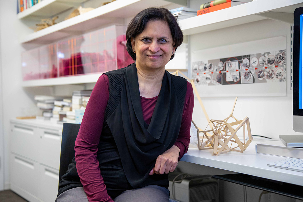 Woman with short dark hair wearing a dark red and black top sitting in a bright lab.