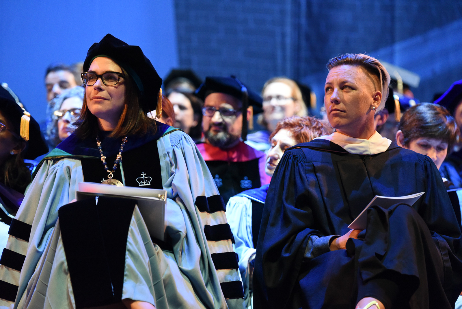 Two women dressed in academic regalia seated together