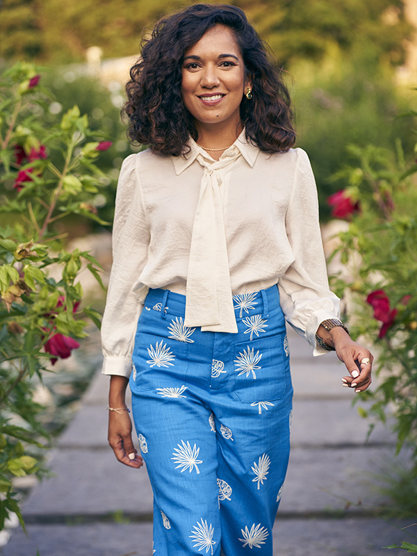 Jenn Chowdhury walks down a garden path with roses