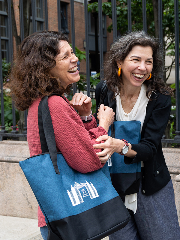 Laughing and Reuniting, two alumnae embrace