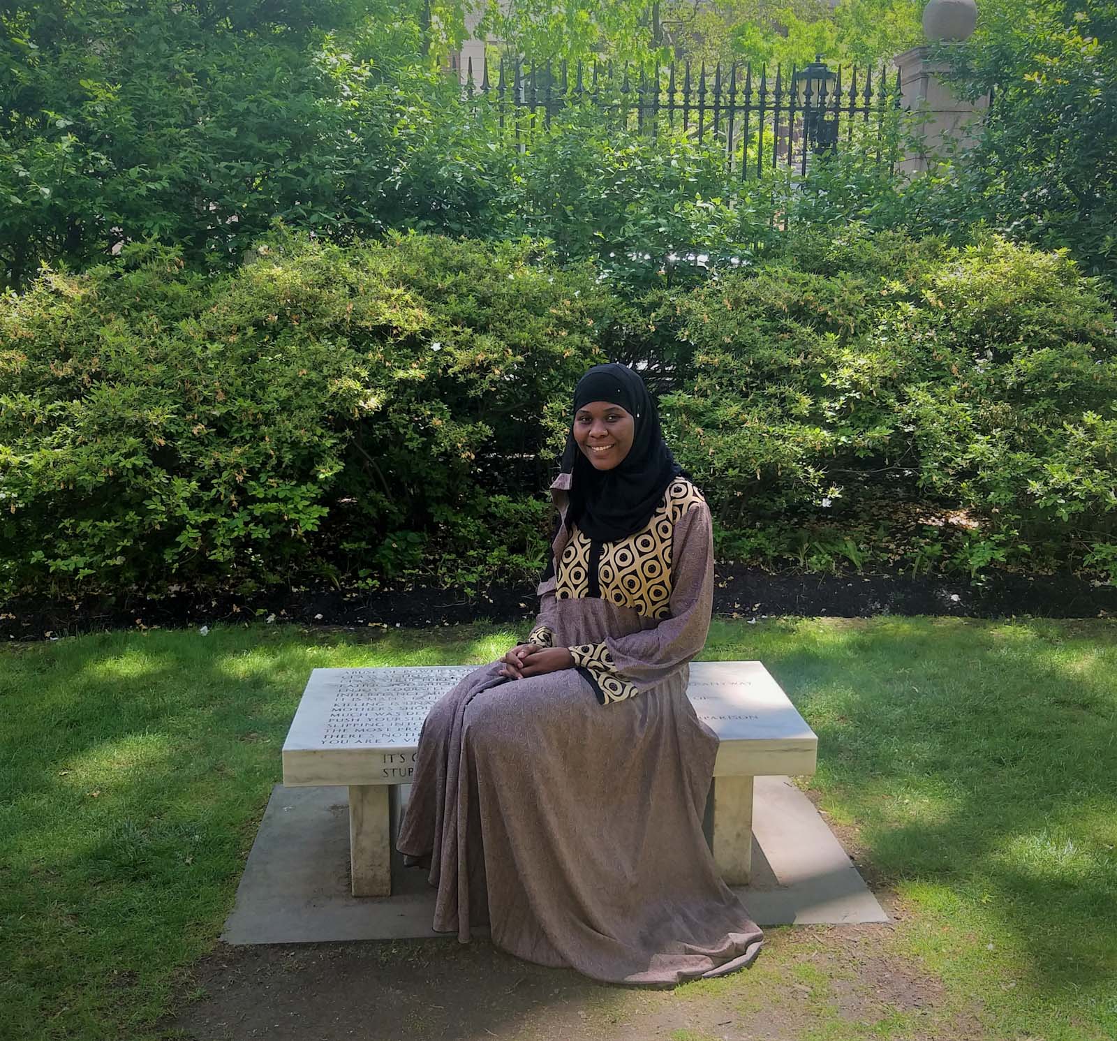 Hawa Tunkara ’21 seated on a bench on Barnard's campus