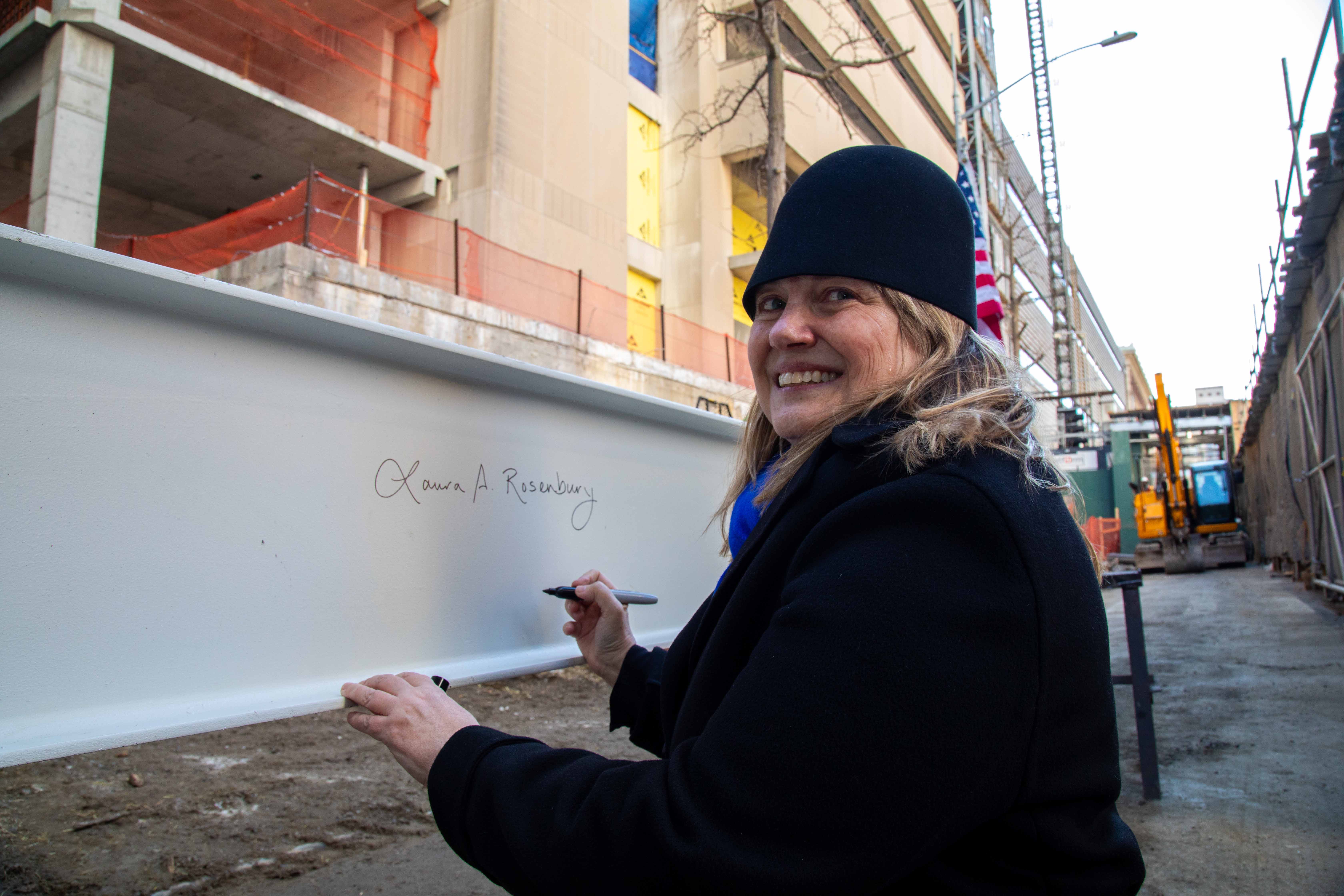 President Laura Rosenbury signing a metal beam