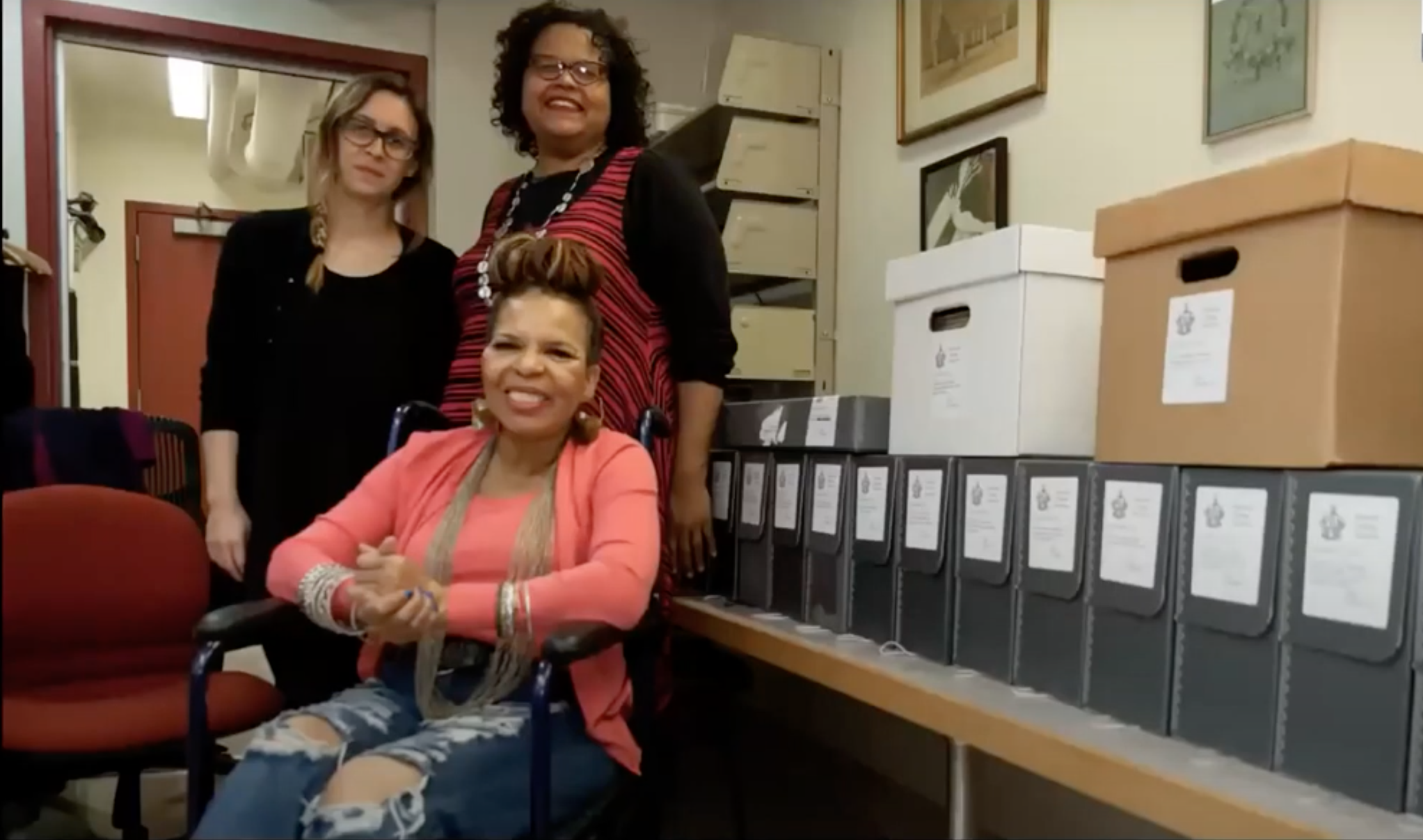 Two women standing behind seated Ntozake Shange