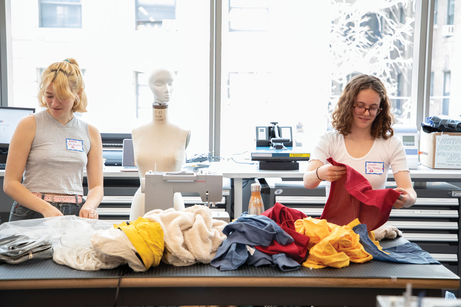 2 students sorting clothing on a large table