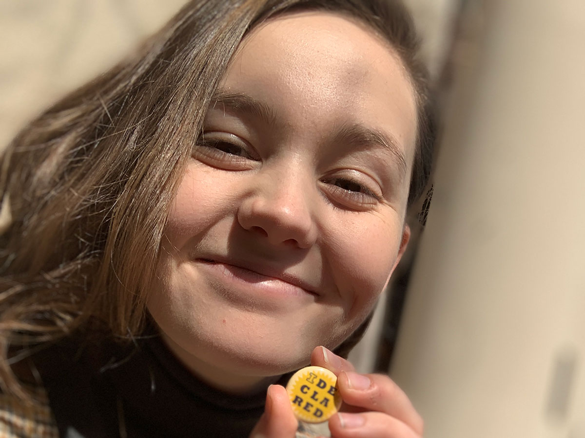 Young woman holding I declared button