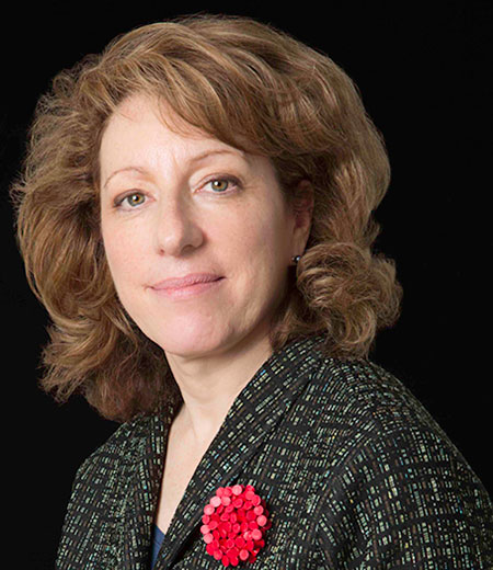 Side profile of woman with light brown hair and red flower on lapel.