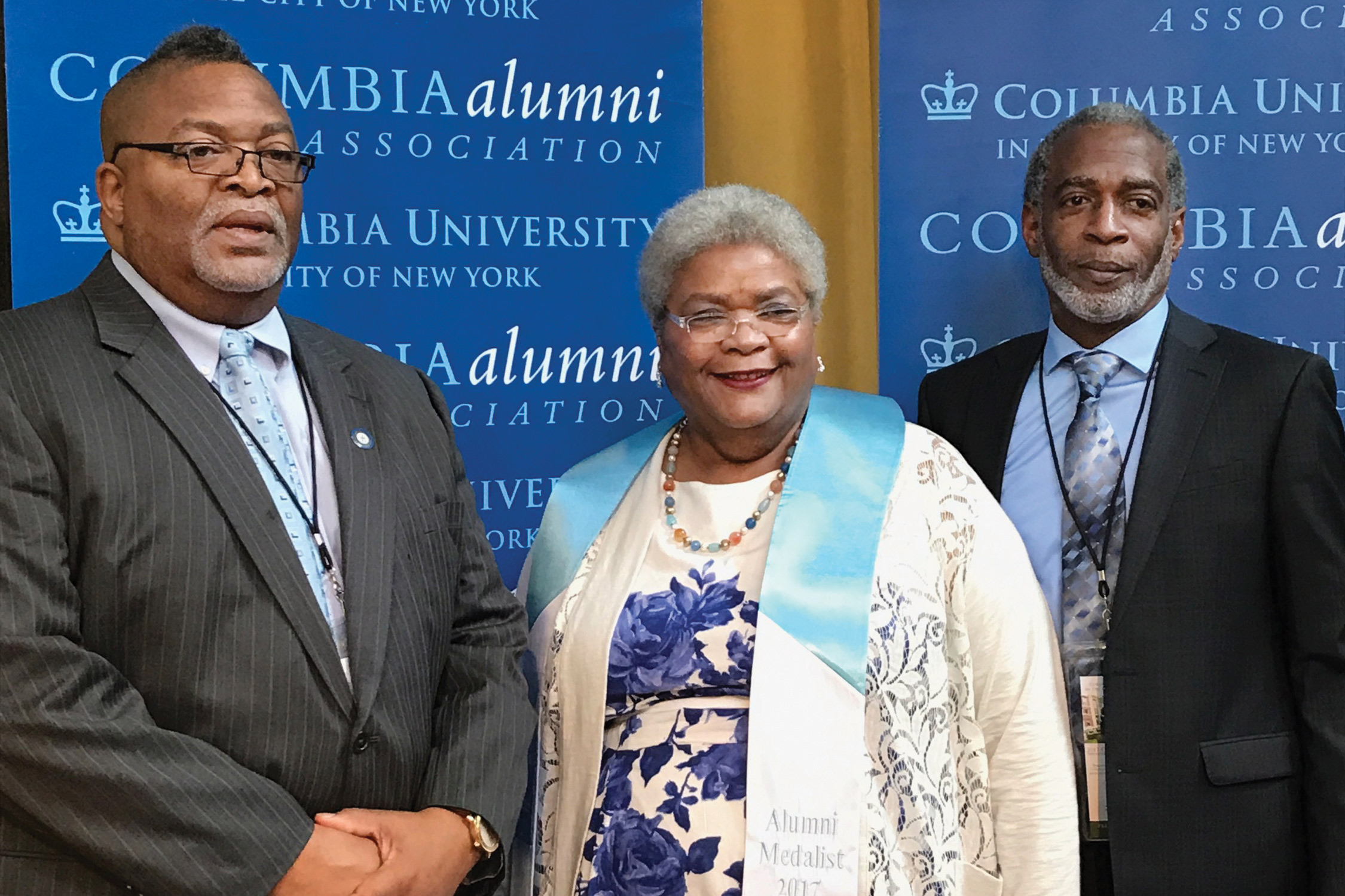 Woman accompanied by husband and brother as she receives an award.