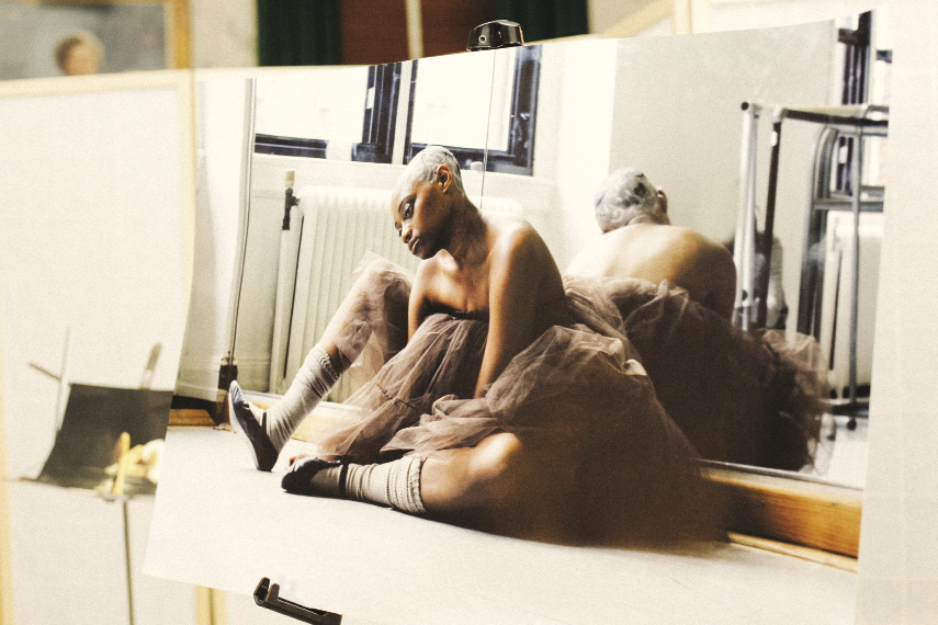 ballet dancer resting on the floor with her back to a mirror