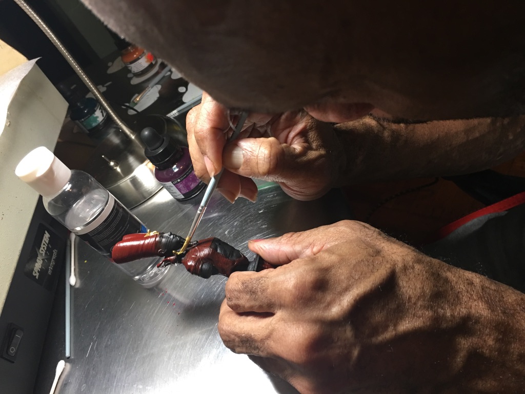 Aaron hand paints a chess piece.