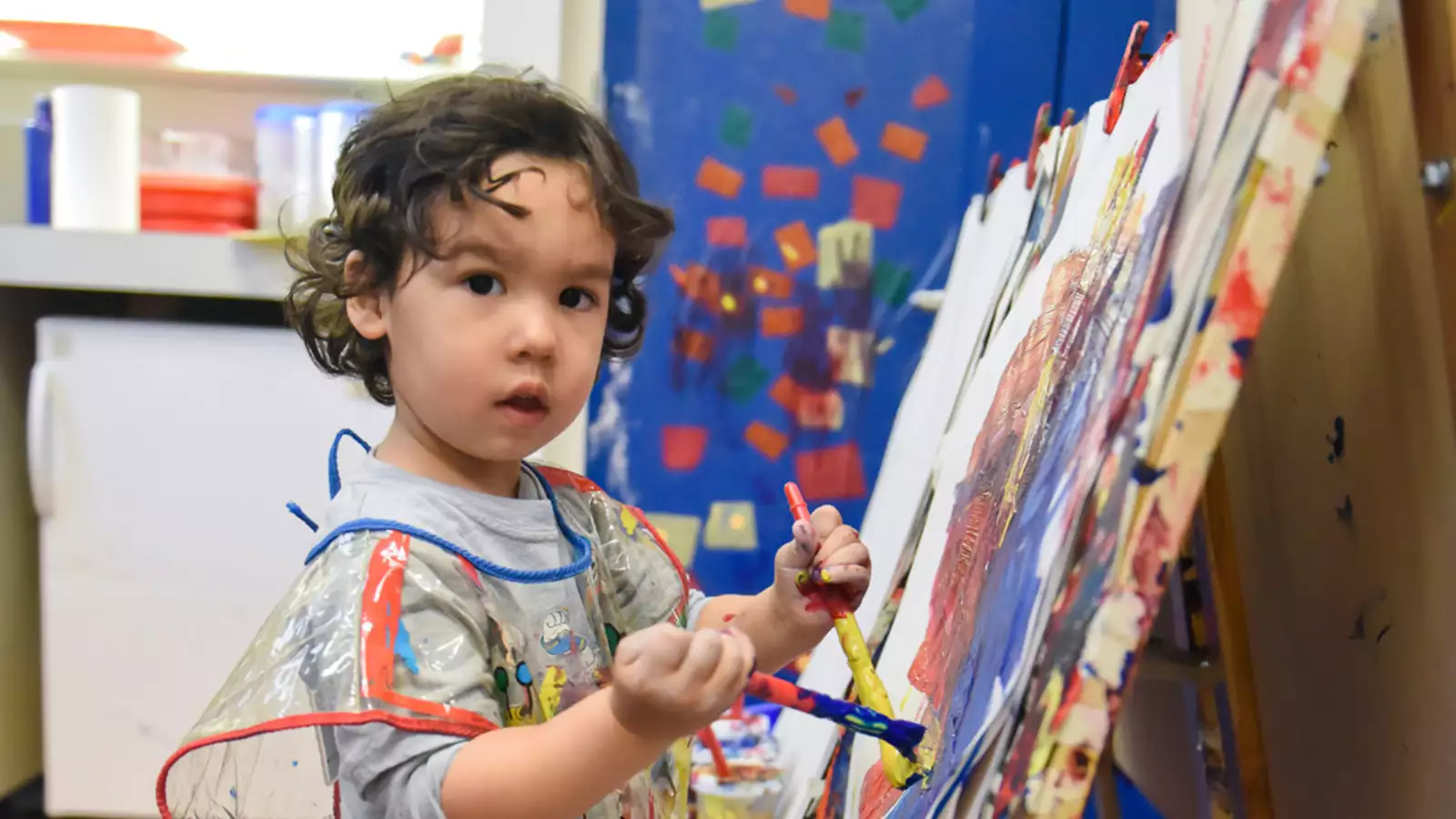 Toddler painting at easel