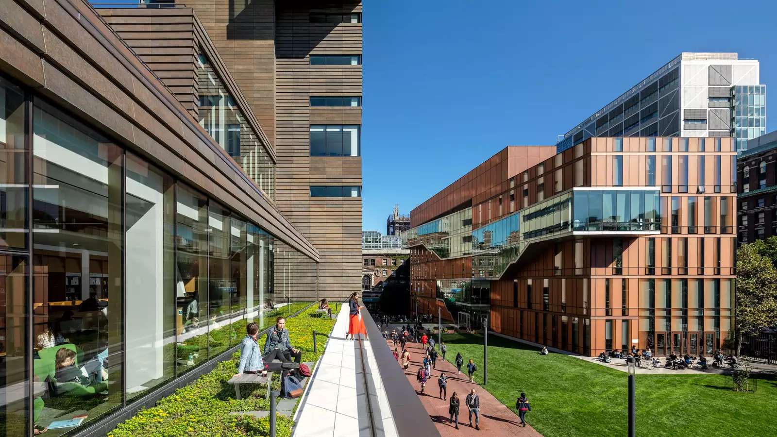 A view of Barnard's campus with students on Milstein's terrace, students walking on the sidewalk, and the Diana Center in the distance