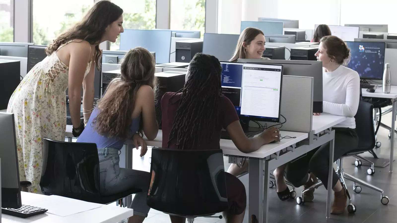 Students in the CSC classroom look at a computer screen together.