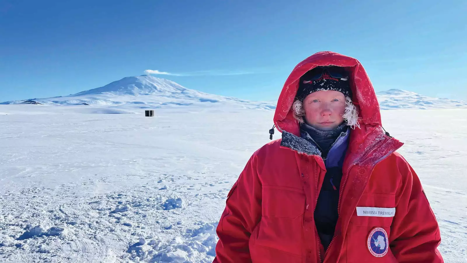 Marissa Tremblay in Antarctica. She is wearing a large red coat with the hood up.