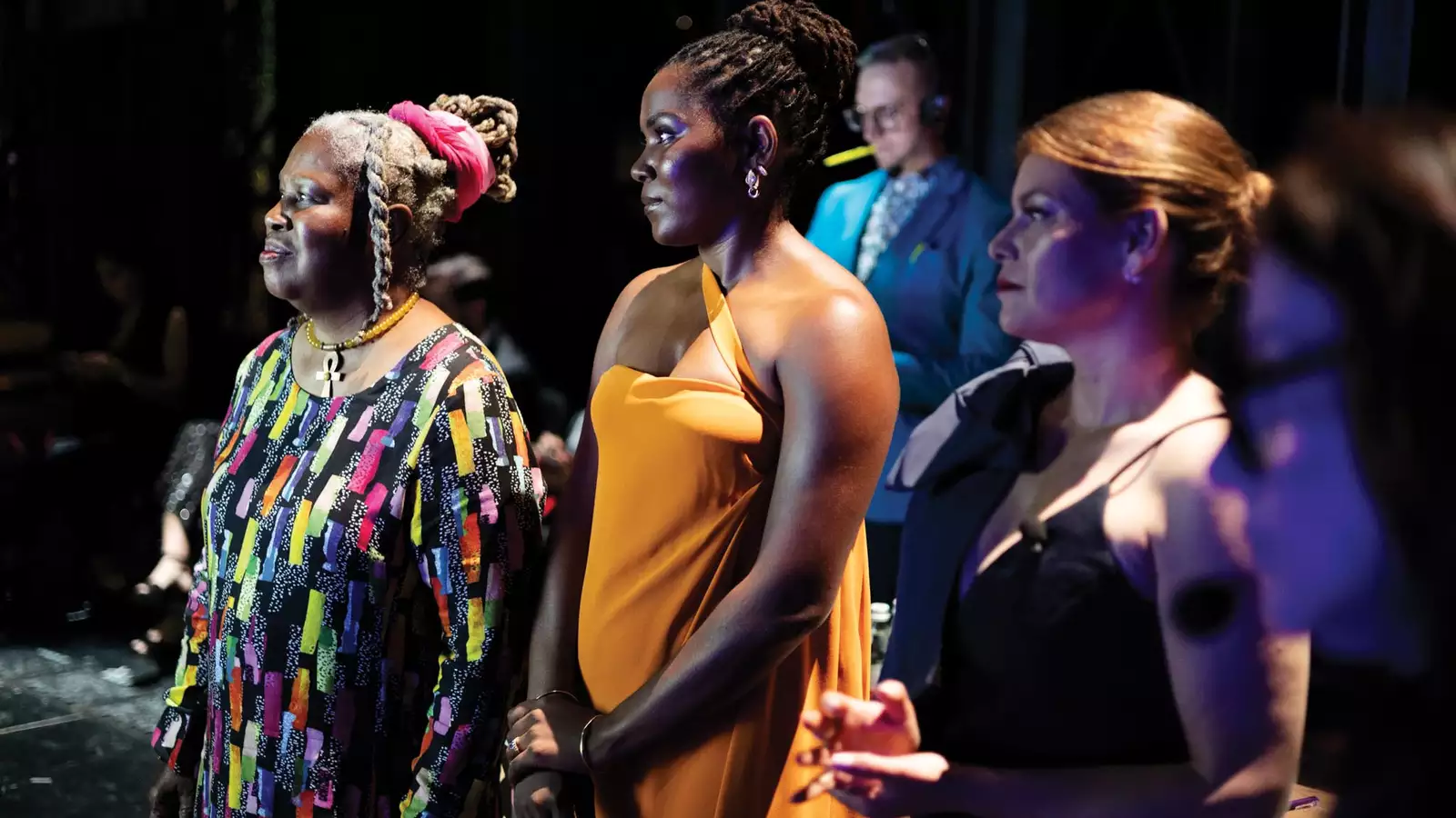 Olivia watkins looking to the left standing on a stage with other women