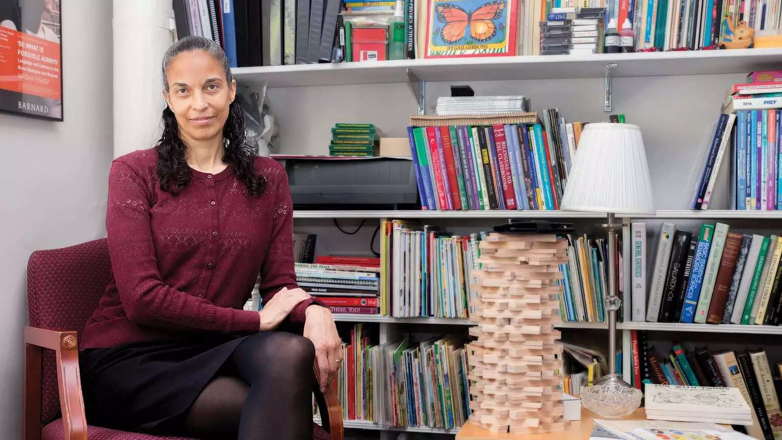 Maria Rivera Maulucci ’88 seated in front of a bookshelft full of kids books