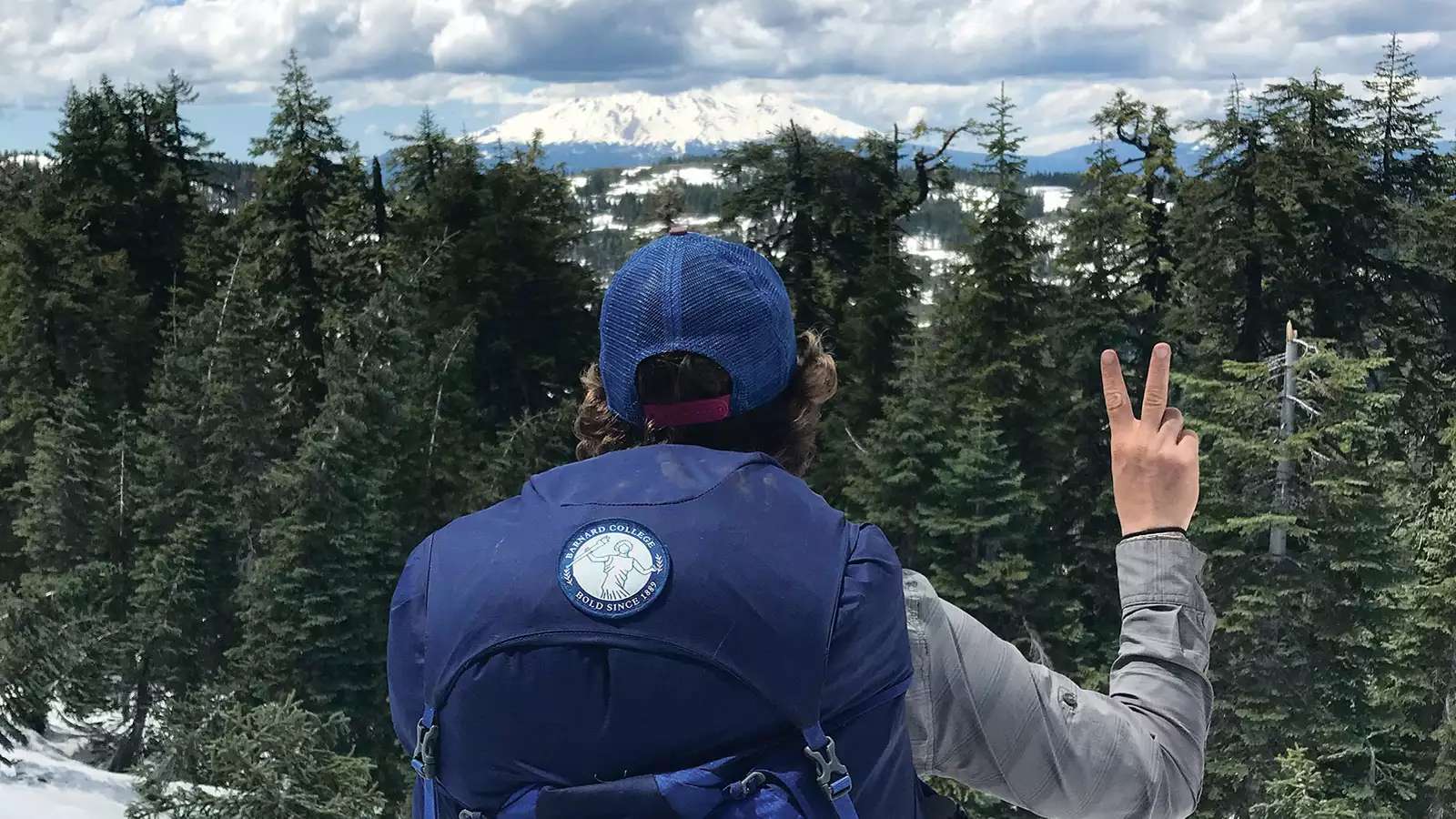 Woman backpacking and looking over a pine forest