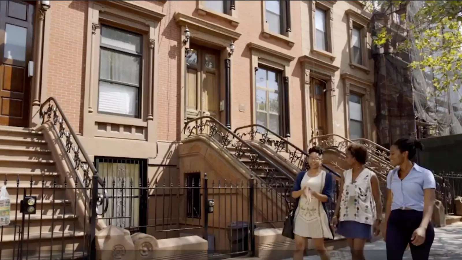 3 young Black people walk down a street in Harlem