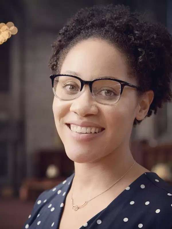 Jalisha Jenifer positioned to the right wearing glasses with chandelier in background