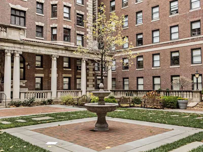 Shows Arthur ross courtyard fountain, pavers and grass in the middle of the quad of dorm buildings