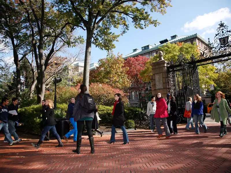 Students walking on campus near entrance gates in the fall