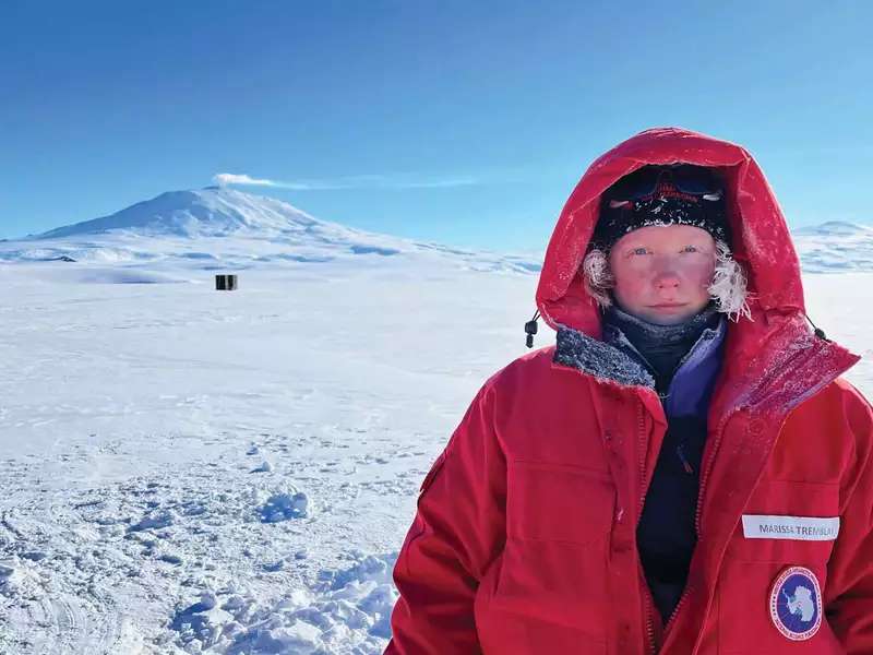 Marissa Tremblay in Antarctica. She is wearing a large red coat with the hood up.