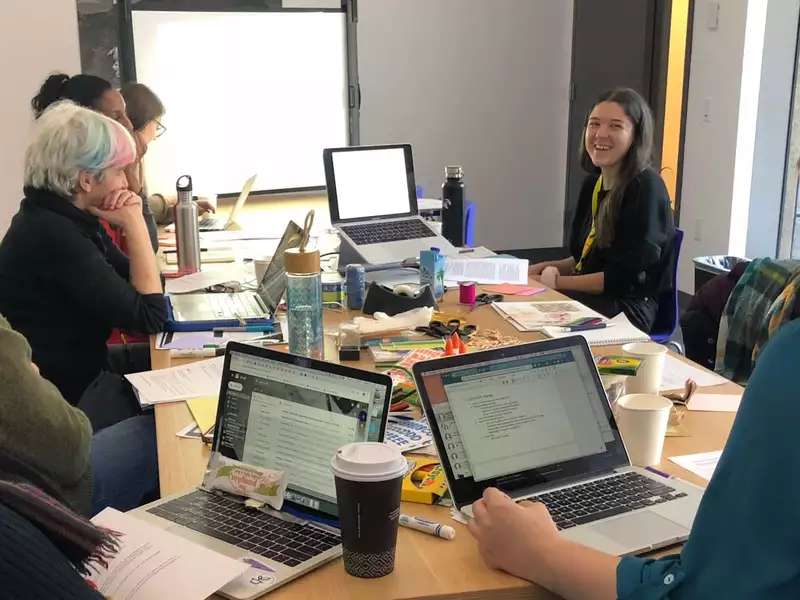 Students around a conference table with open laptops