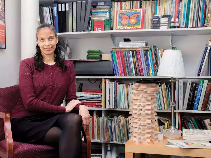 Maria Rivera Maulucci ’88 seated in front of a bookshelft full of kids books