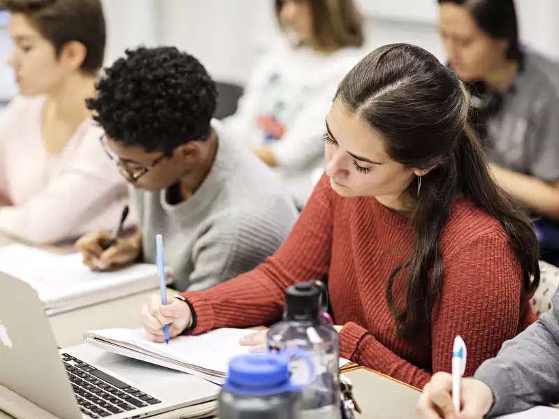 students in a classroom, writing in notebooks