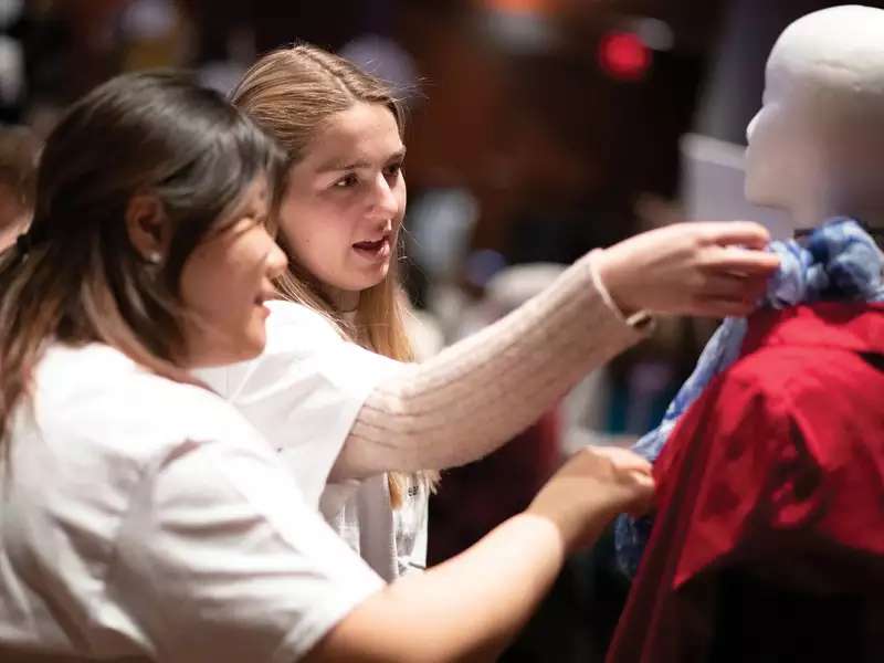 2 students adjusting the clothes on a mannequin