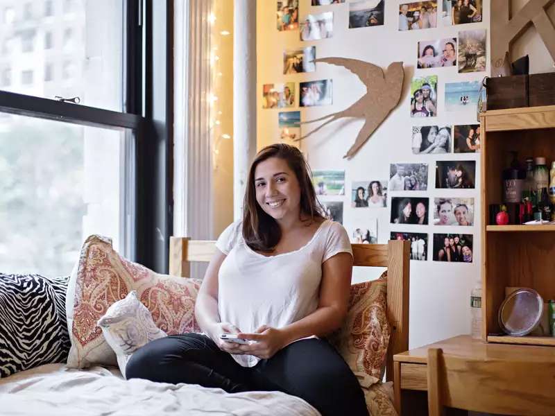 student relaxes on her bed in her dorm room