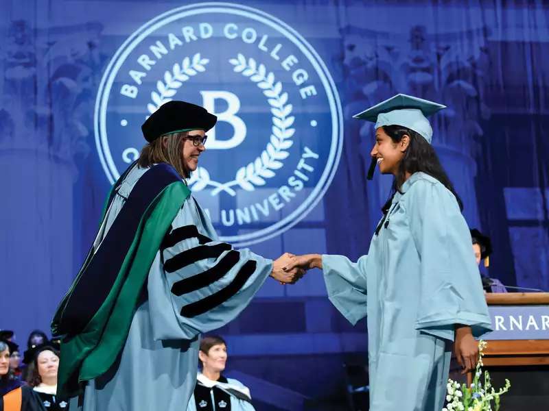 Commencement stage and president shakes hands with a graduating student