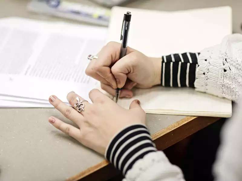 Close-up of a person's hands writing on paper